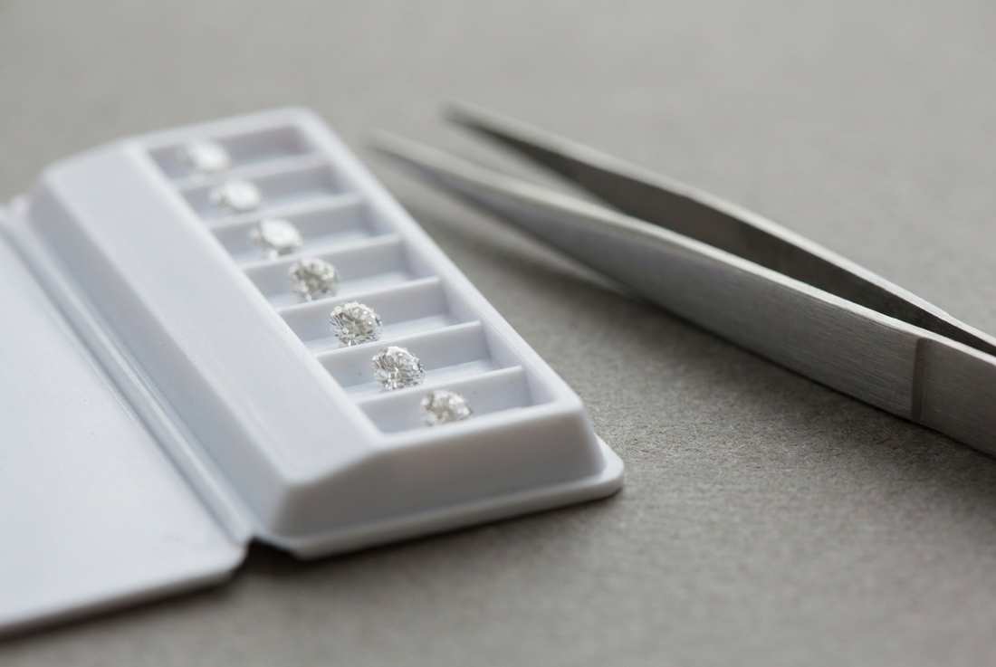 Master comparison stones in a grading tray beside steel tweezers